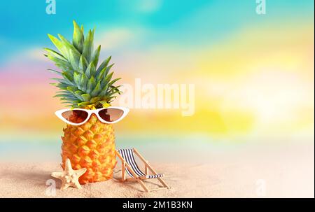 Ananas con occhiali da sole su sfondo tropicale spiaggia. Concetto estivo. Foto Stock