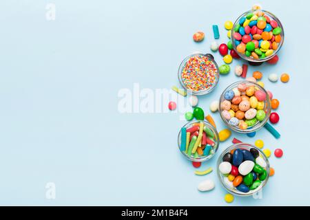 caramelle tonde di colore diverso in ciotola e vasetti. Vista dall'alto di una grande varietà di dolci e caramelle con spazio copia. Foto Stock