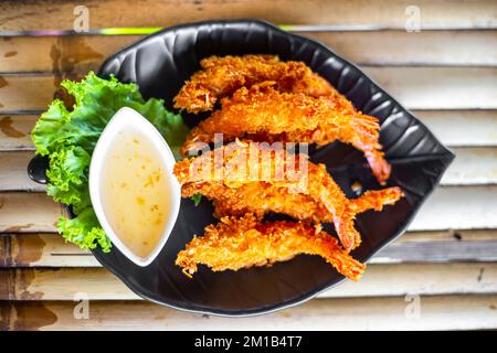 Gamberetti fritti in pastella con salsa su un piatto, fuoco selettivo. Delizioso cibo tailandese. Foto Stock