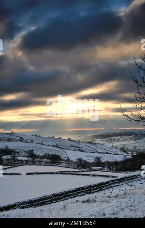 La neve copre i terreni agricoli dello Yorkshire Dales National Park mentre il sole tramonta. Foto Stock