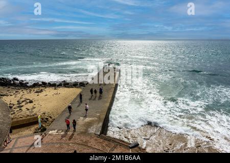 Un momento di tranquillità sul piccolo molo accanto al faro di Maspalomas, dove la gente gode della tranquillità dell'oceano e della bellezza di Gran Canaria Foto Stock