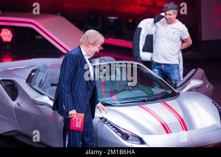 11 dicembre 2022, Renania settentrionale-Vestfalia, Hürth: Thomas Gottschalk (l), presentatore, si trova accanto ad una Ferrari appartenente al milionario della lotteria Kürsat Yildirim, alias 'Chico,' in studio durante la revisione annuale di RTL 'People, Images, Emotions 2022.' Foto: Rolf Vennenbernd/dpa Foto Stock