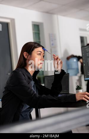 Sviluppatore di Web asiatico pensivo che lavora allo sviluppo di codice html e idee di brainstorming per creare script di codifica. Ingegnere IT che pensa al server di database nell'ufficio dell'agenzia IT per i big data Foto Stock