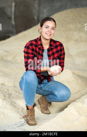 Donna agronomo positiva che squatting a mazzo di farina di mais Foto Stock