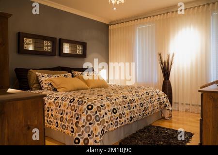 Letto king size con motivi floreali copriletto nella camera da letto principale all'interno di uno stile casa su due livelli. Foto Stock