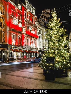 Percorsi leggeri da un'auto di lusso illuminata all'esterno dell'iconico negozio Cartier di Londra durante la stagione natalizia. Foto Stock