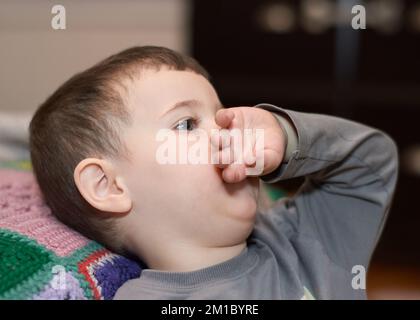 Giovane ragazzo espressivo che guarda i cartoni animati nel soggiorno Foto Stock