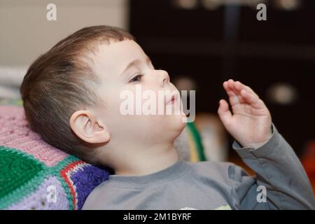 Giovane ragazzo espressivo che guarda i cartoni animati nel soggiorno Foto Stock