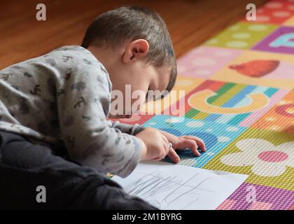 ragazzo che disegnava un pezzo di carta nella sua stanza Foto Stock