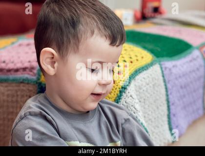 Giovane ragazzo espressivo che guarda i cartoni animati nel soggiorno Foto Stock