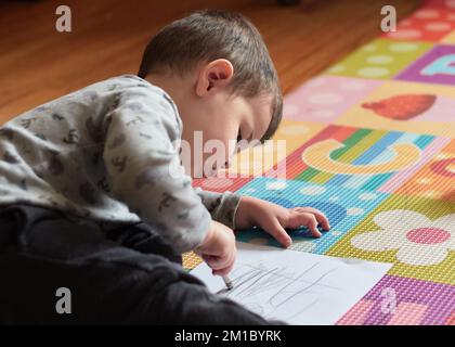 ragazzo che disegnava un pezzo di carta nella sua stanza Foto Stock