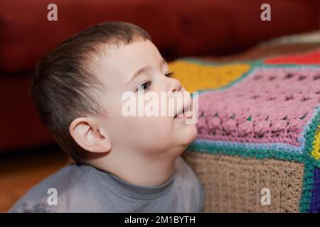 Giovane ragazzo espressivo che guarda i cartoni animati nel soggiorno Foto Stock