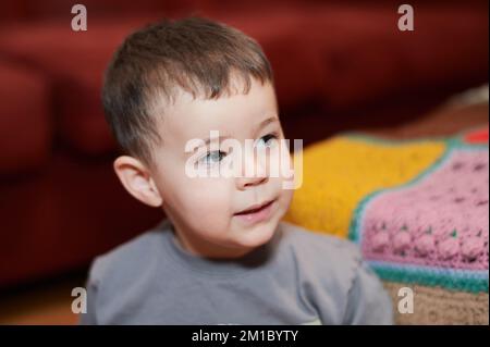 Giovane ragazzo espressivo che guarda i cartoni animati nel soggiorno Foto Stock