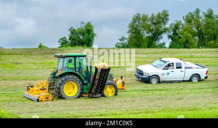 NEW ORLEANS, LA, USA - 6 SETTEMBRE 2022: Trattore che taglia erba sul fiume Mississippi Levee e camion che appartiene alla Flood Protection Authority Foto Stock