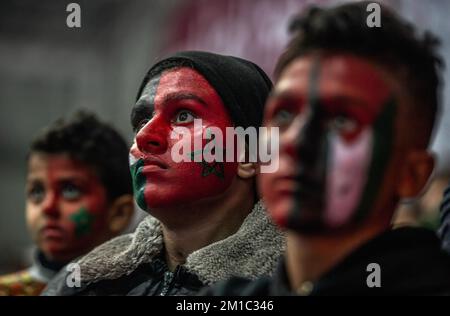 Gaza, Palestina. 10th Dec, 2022. I giovani palestinesi con i volti dipinti delle bandiere del Marocco e della Palestina guardano con attenzione la trasmissione dal vivo della finale della Coppa del mondo FIFA tra Marocco e Portogallo, che si è tenuta in Qatar, al Saad Sayel Sports Hall di Gaza City. (Punteggio finale; Marocco 1-0 Portogallo) Credit: SOPA Images Limited/Alamy Live News Foto Stock