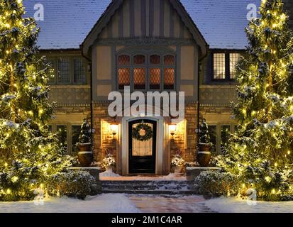 Cortile di casa con luci decorative vacanza su pini in inverno Foto Stock