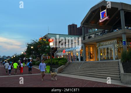 La gente cammina tra i negozi, i ristoranti e i caffè del quartiere Inner Harbor, un'area di intrattenimento e affari a Baltimora Foto Stock