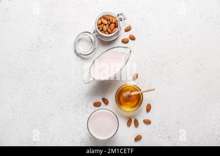 Composizione con latte di mandorla sano, noci e miele su sfondo chiaro Foto Stock