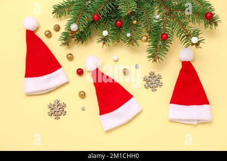 Composizione con cappelli di Santa, rami di abete e decorazioni natalizie su sfondo colorato Foto Stock