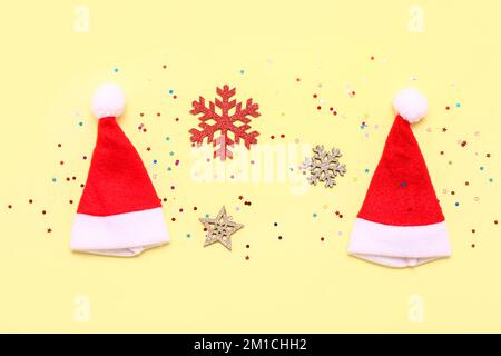 Composizione con cappelli di Babbo Natale, fiocchi di neve e paillettes su sfondo colorato Foto Stock