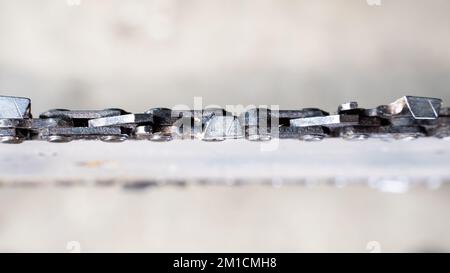 Primo piano di una catena di motosega su uno pneumatico su uno sfondo sfocato, vista dall'alto Foto Stock