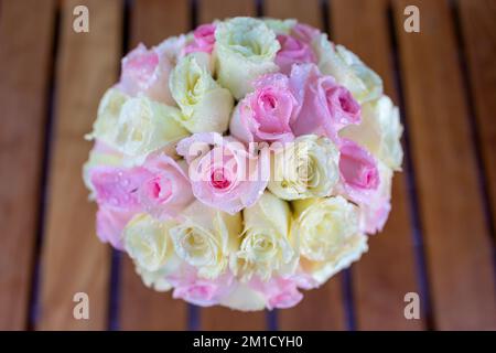 Un grande bouquet di rose in un bicchiere sul tavolo ci sono gocce d'acqua sui petali sembrano freschi e belli con fiori rosa e giallo Foto Stock