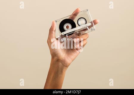 Crop anonima afro-americana donna che mostra vintage retro cassetta nastro su sfondo beige Foto Stock