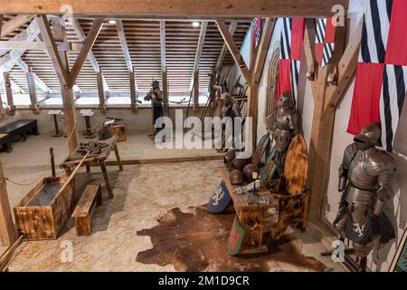 Interno del castello di Predjama, Slovenia, sala d'armeria medievale con armature a piastra completa, scudi, armi, caschi e guanti. Foto Stock