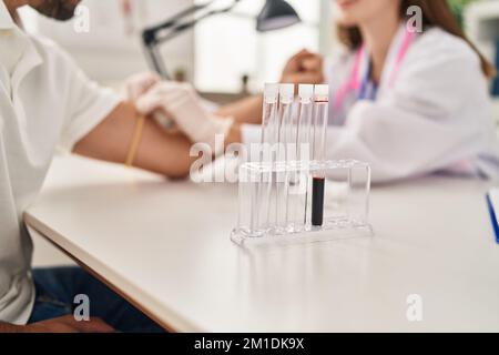 L'uomo e la donna che indossano l'uniforme del medico che hanno analisi del sangue in clinica Foto Stock