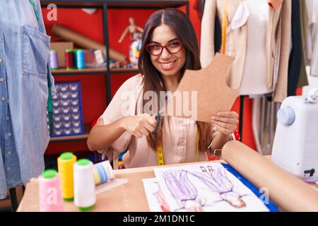 Giovane bella donna araba su misura sorridente sicuro tagliando carta presso atelier Foto Stock