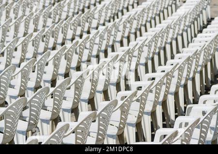 Sedie bianche in plastica disposte in file in un'area concerti all'aperto Foto Stock