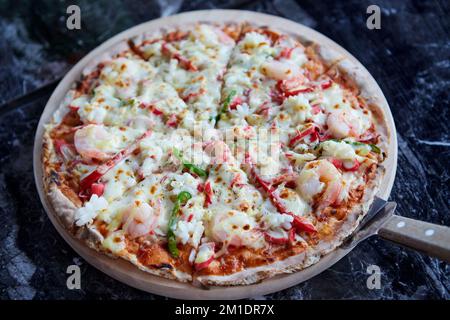 Pizza calda formaggio crosta frutti di mare condimento salsa verdure su vassoio di legno Foto Stock