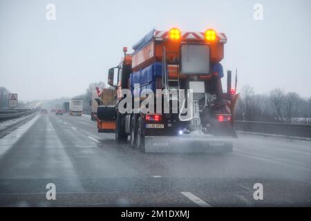 12 dicembre 2022, Sassonia, Schkeuditz: Un veicolo da vaiolatura del servizio di sdoganamento invernale guida sull'autostrada 9 e diffonde il sale sulla carreggiata. La nuova settimana inizia anche in Germania. Nelle prime ore del mattino, il termometro mostrava meno 8 gradi ad Hannover, meno 6 gradi a Brema e meno 5 gradi a Passau. A livello regionale - molto probabilmente nel sud della Germania - ci potrebbe essere brina grave con bassa copertura nuvolosa sulla neve, aveva predetto i meteorologi del servizio meteorologico tedesco (DWD) a Offenbach. Un'eccezione sarebbe le coste con temperature intorno a 0 d Foto Stock