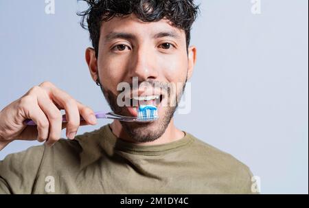 Primo piano dell'uomo che gli sfiorava i denti isolato, il volto dell'uomo bello che gli sfiorava i denti. Concetto di pulizia e cura dei denti. Viso del ragazzo spazzolando denti isol Foto Stock