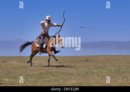 Il nomade del Kirghizistan spara frecce su un bersaglio mentre galoppa, il lago Song kol, la regione di Naryn, il Kirghizistan Foto Stock