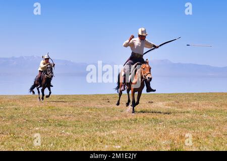 Il nomade del Kirghizistan spara frecce su un bersaglio mentre galoppa, il lago Song kol, la regione di Naryn, il Kirghizistan Foto Stock