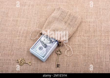 Chiave retrò e il pacchetto del dollaro USA in un sacco su una tela di canapa Foto Stock