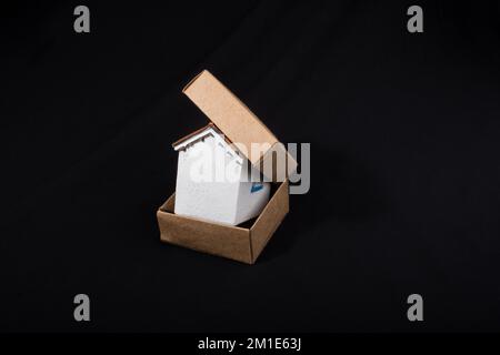 Modello di piccola casa in mano in una scatola di carta Foto Stock