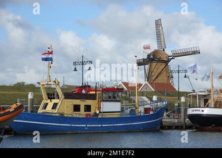 Porto con navi al muro di banchina e mulino a vento a Oudeschild, Texel, Oudeschild, Texel, Olanda del Nord, Olanda, Paesi Bassi Foto Stock