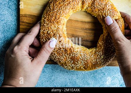 Vista dall'alto di una donna che tiene un anello di pane greco al sesamo (Koulouria) Foto Stock