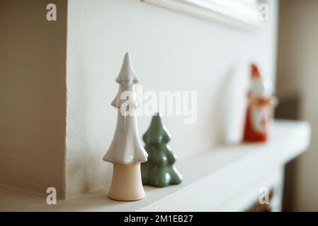 Primo piano di alberi di Natale in ceramica su una mantelpiece camino Foto Stock