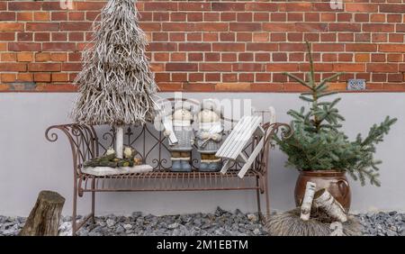 Decorazioni invernali con albero di Natale, bambole e slitte davanti a una casa Foto Stock