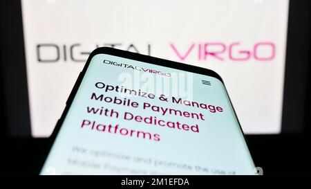 Smartphone con pagina Web della società di pagamento francese Digital Virgo S.A. sullo schermo di fronte al logo aziendale. Messa a fuoco in alto a sinistra del display del telefono. Foto Stock