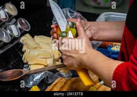 Un primo piano di una donna che prepara le zucchine in cucina Foto Stock