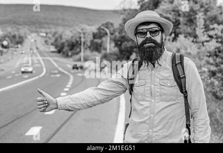 Uomo prova arresto macchina pollice in su. Viaggio con arresto automatico. Hitchhiking uno dei modi più economici di viaggiare. Gli Hitchhikers possono incontrare molta gente e fare i lotti amici Foto Stock