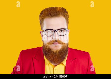 Uomo bearded che indossa giacca e occhiali rossi che guardano la fotocamera con espressione seria del volto Foto Stock