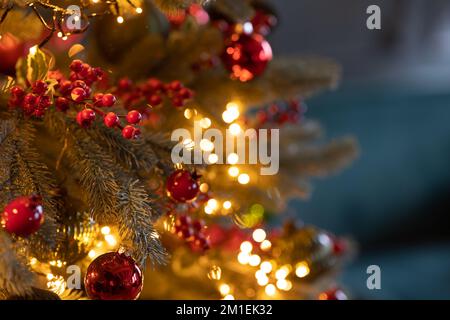 Primo piano dell'albero di Natale decorato festivamente con palline rosse luminose su sfondo fiabesco frizzante. Luci di ghirlanda sfocate, effetto Bokeh. DEF Foto Stock