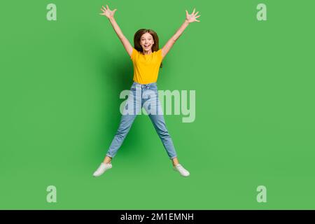 Ritratto integrale della persona soddisfatta attiva che salta le braccia alzate isolato su sfondo di colore verde Foto Stock