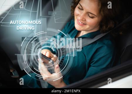 Il conducente donna controlla un'auto autonoma utilizzando uno smartphone Foto Stock