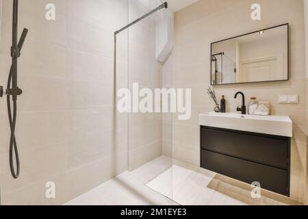 un bagno moderno con piastrelle bianche e finiture nere nella cabina doccia, è tutto pronto per l'uso Foto Stock